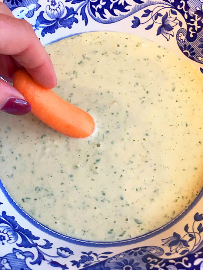 Tahini salad dressing dipping a carrot into bowl dipping carrot into tahini dip bowl fountainof30