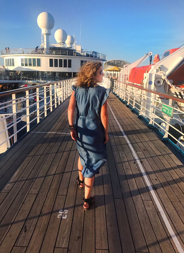 Permission To Hustle cruise experience woman in denim dress walking pier