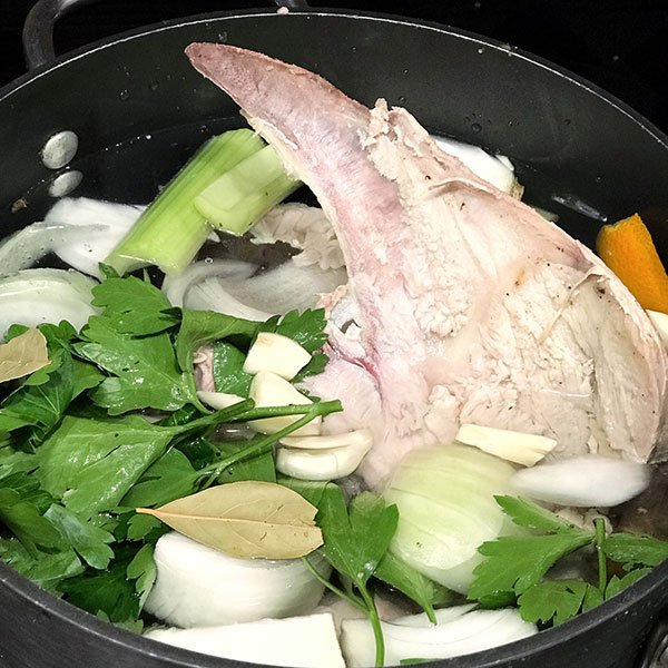 Bone Broth bone garlic celery green leaf seasonings in a pan fountainof30