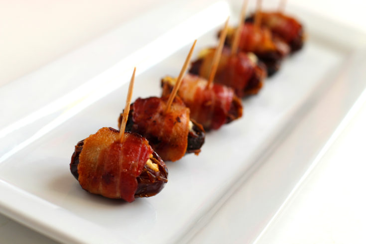 Bacon wrapped dates with goat cheese on a plate