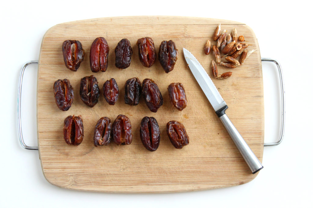 Bacon Wrapped Dates With Goat Cheese Dates on a wooden board with knife