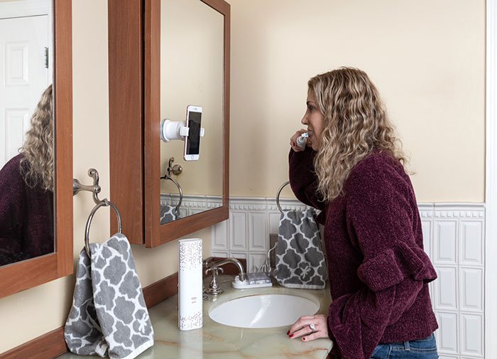 Oral-B GENIUS 8000 woman brushing teeth in mirror