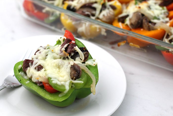 Keto Philly Cheesesteak Stuffed Peppers colorful peppers in glass pan with serving on white plate