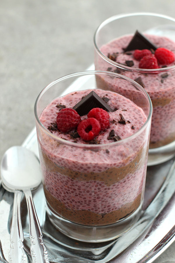 Layered pudding pink and brown with chocolate and raspberry garnish served in glasses on silver tray
