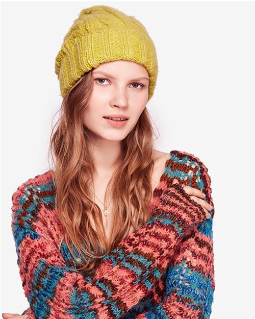 model in gold cable knit beanie with multi-color knit sweater