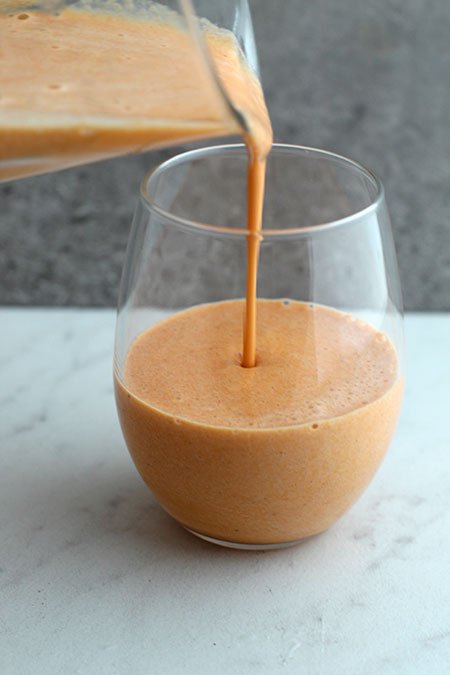 Anti-Inflammatory Golden Milk Smoothie pouring form blender into a glass
