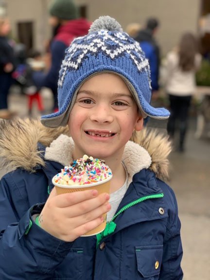 boy with hat smiling with a hot chocolate