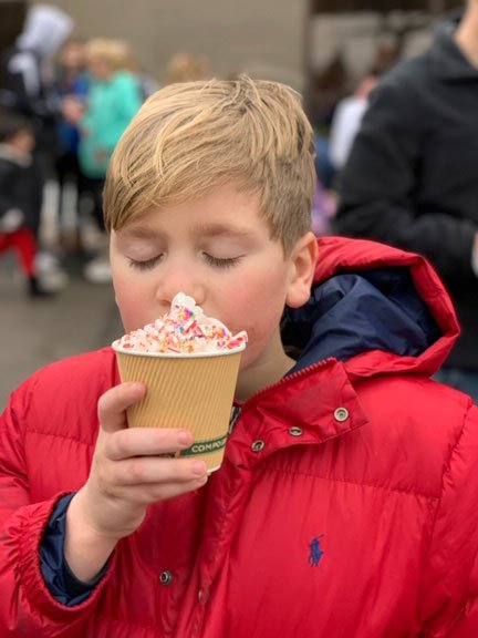 boy with red coat and whipped cream in a cup