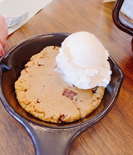 warm chocolate chip cookie in a skillet with a scoop of vanilla ice cream