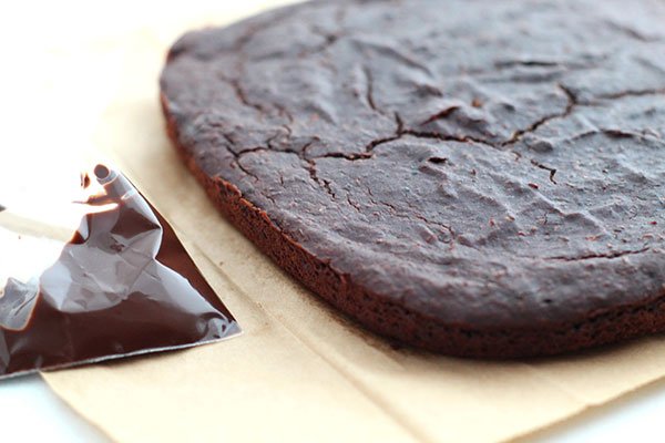 Dark Chocolate Zucchini Brownies out of pan with baggie of chocolate icing