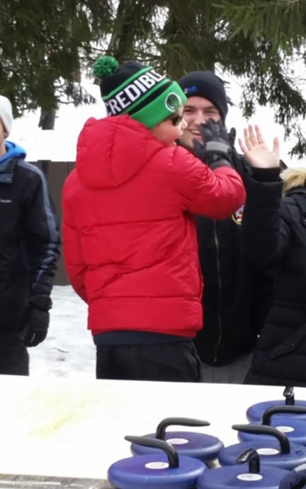 boy in hat and winter coat getting high fived