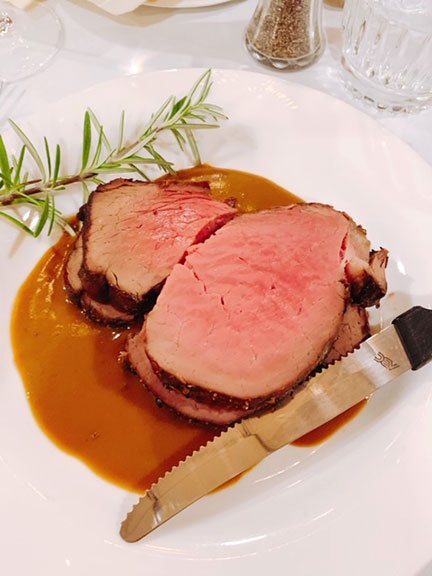 prime rib on a plate with rosemary and steak knife