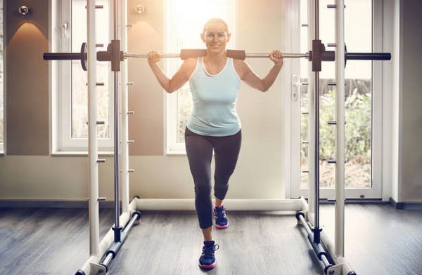 woman over 40 with barbell doing lunges fountainof30