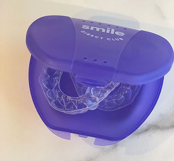 SmileDirectClub see-through aligners in a purple case