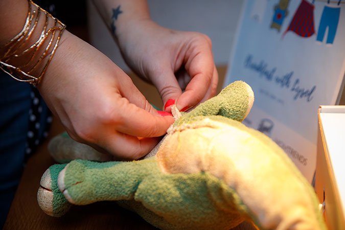 fixing stuffed animal toys close up hands fixing green toy