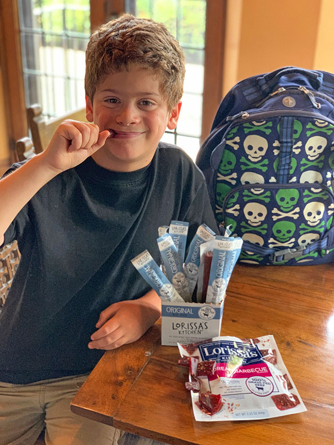 boy enjoying Lorissa's Kitchen snacks kitchen tsble fountainof30