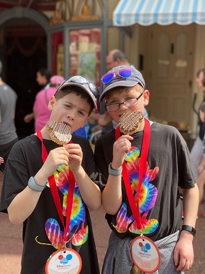 two boys at disney world magic kingdom eating rice krispie treats fountainof30