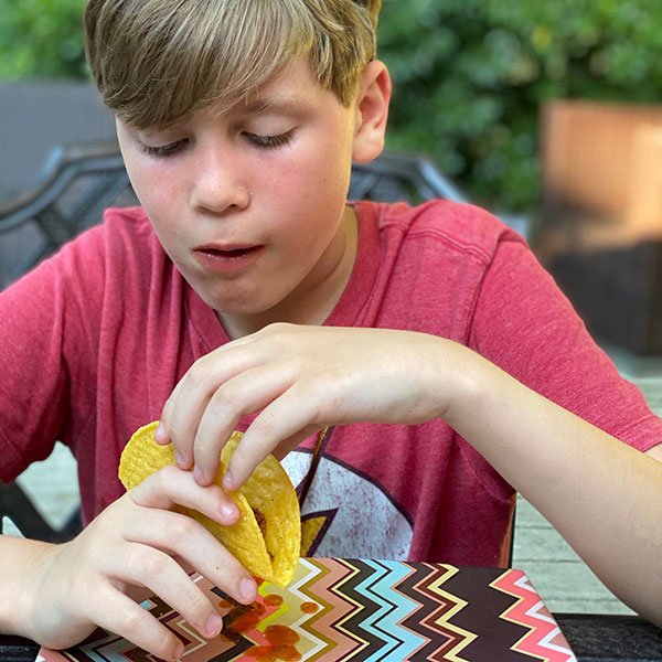 boy with red tshirt eating taco outdoors fountainof30