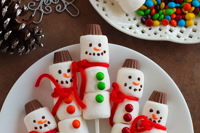 Marshmallow Snowman Pops on a white plate fountain of30