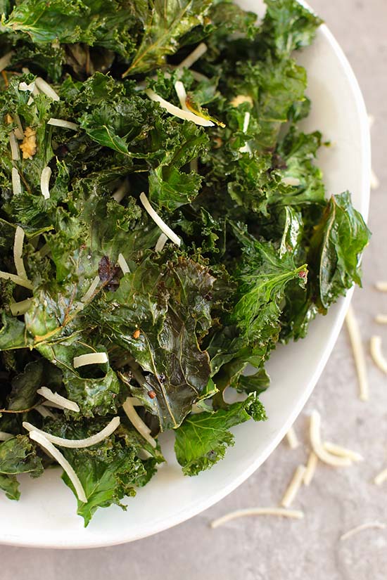 close up baked kale chips in a white bowl fountainof30