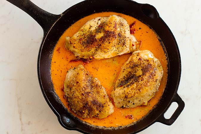 baked chicken and rich sauce in cast iron skillet