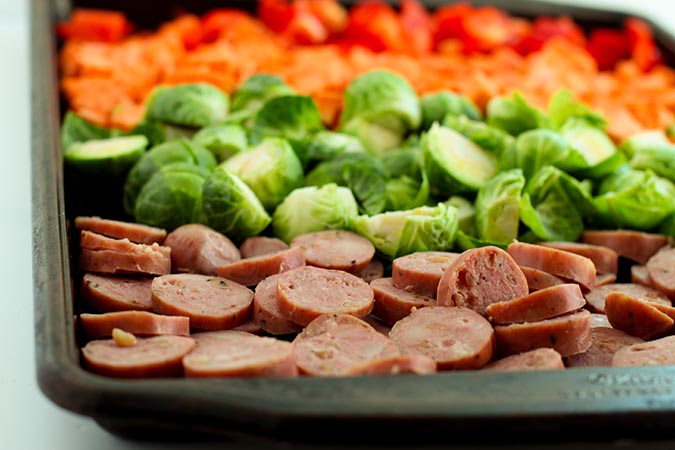 close up sausage and veggetables on baking sheet fountainof30