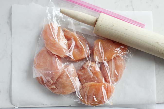 raw chicken breasts in ziplock with rolling pin fountainof30
