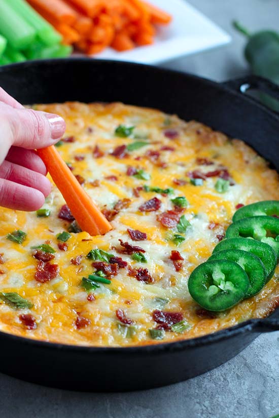 dipping a carrot into jalapeno popper dip fountainof30