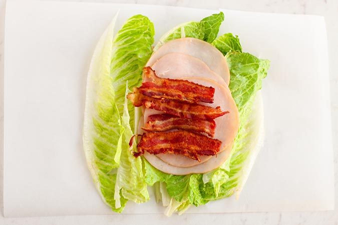 lettuce layered with turkey and bacon on parchment fountainof30