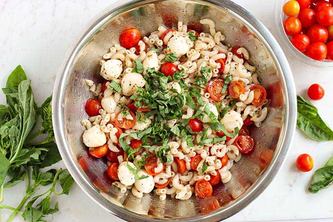 mix caprese pasta salad with sliced fresh basil fountainof30