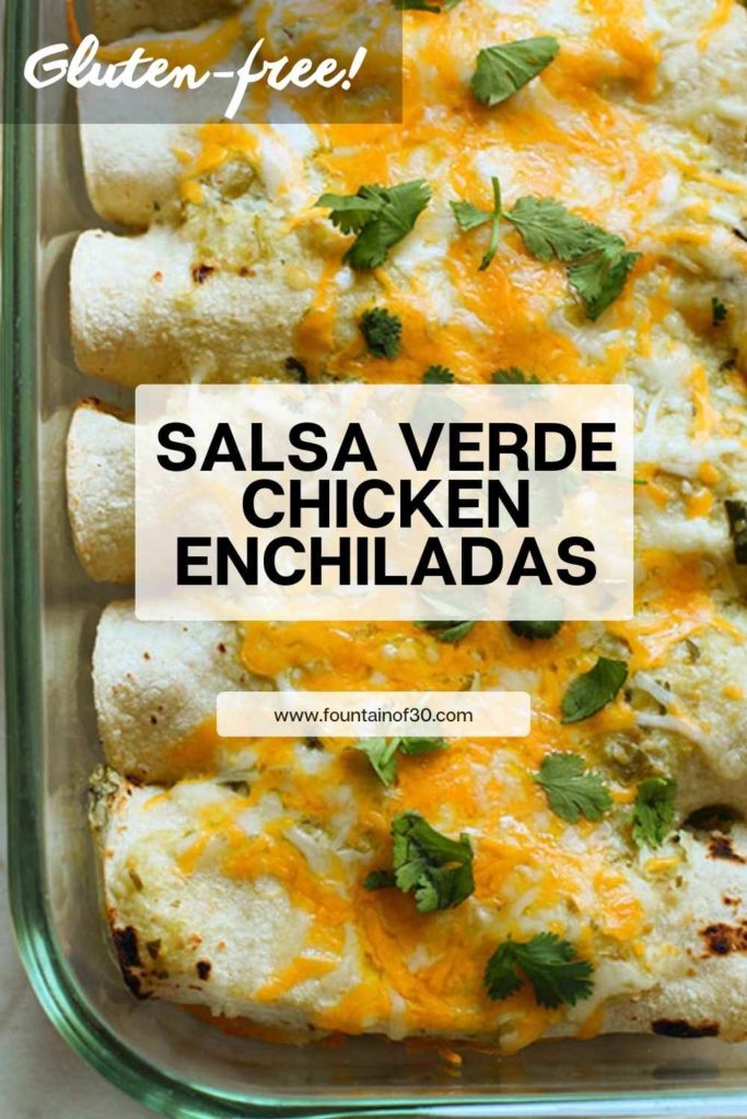 A baking dish filled with golden, cheesy Salsa Verde Chicken Enchiladas, topped with fresh cilantro and a drizzle of sour cream. A gluten-free Mexican dinner made with corn tortillas and tomatillo green salsa.