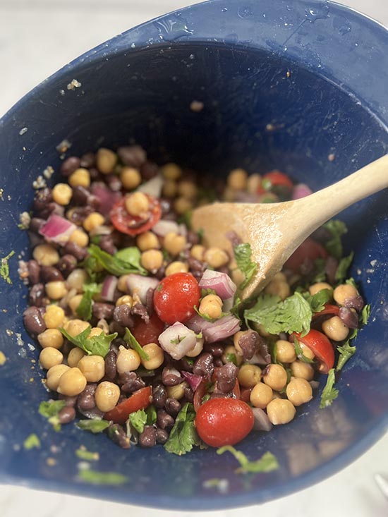 mixing bean salad in blue bowl fountainof30