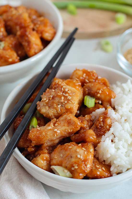 bowls of Sticky Sesame Glazed Chicken with rice and chopsticks fountainof30
